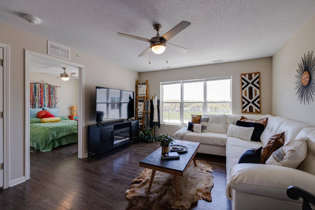a living room with a large window and a ceiling fan
