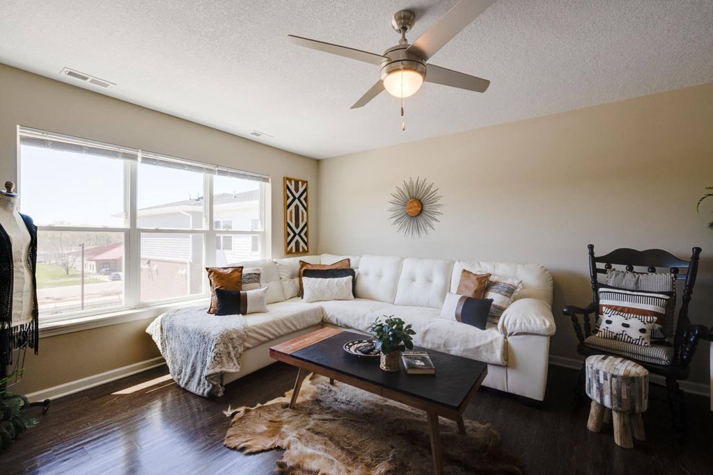 a living room with a large window and a ceiling fan