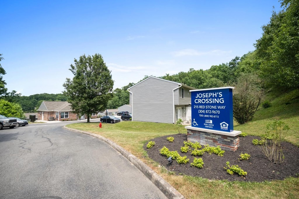 the sign is in front of a property with a road and trees