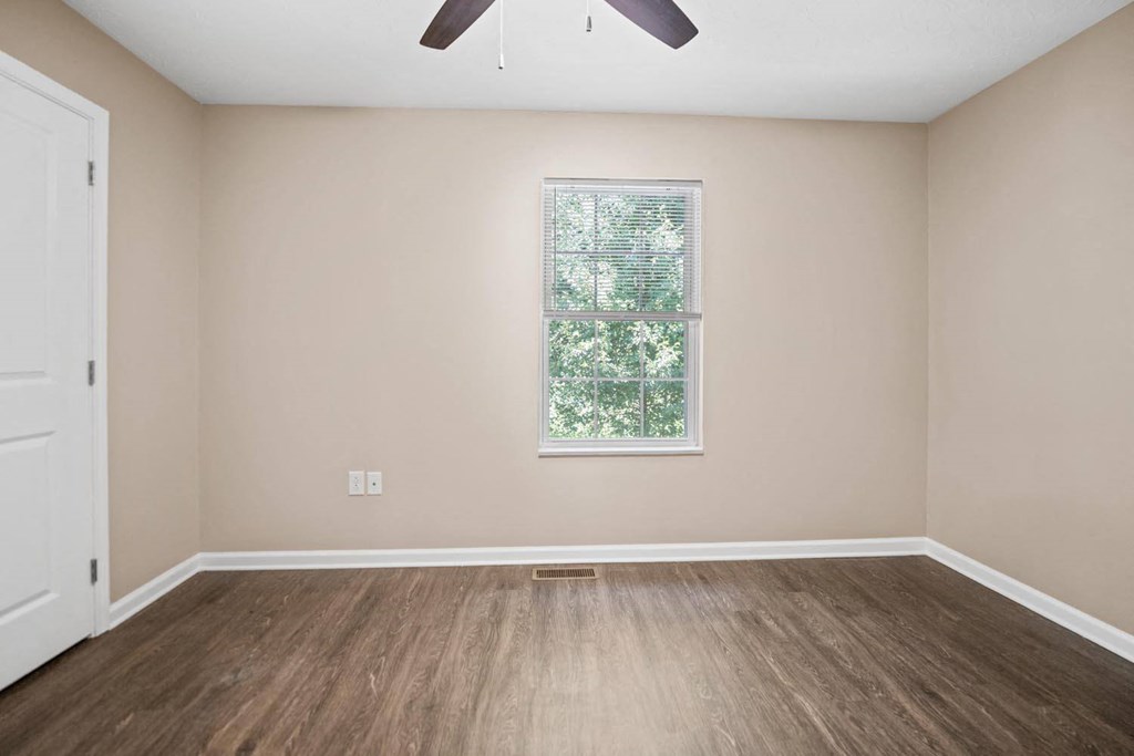 an empty living room with wood floors and a window
