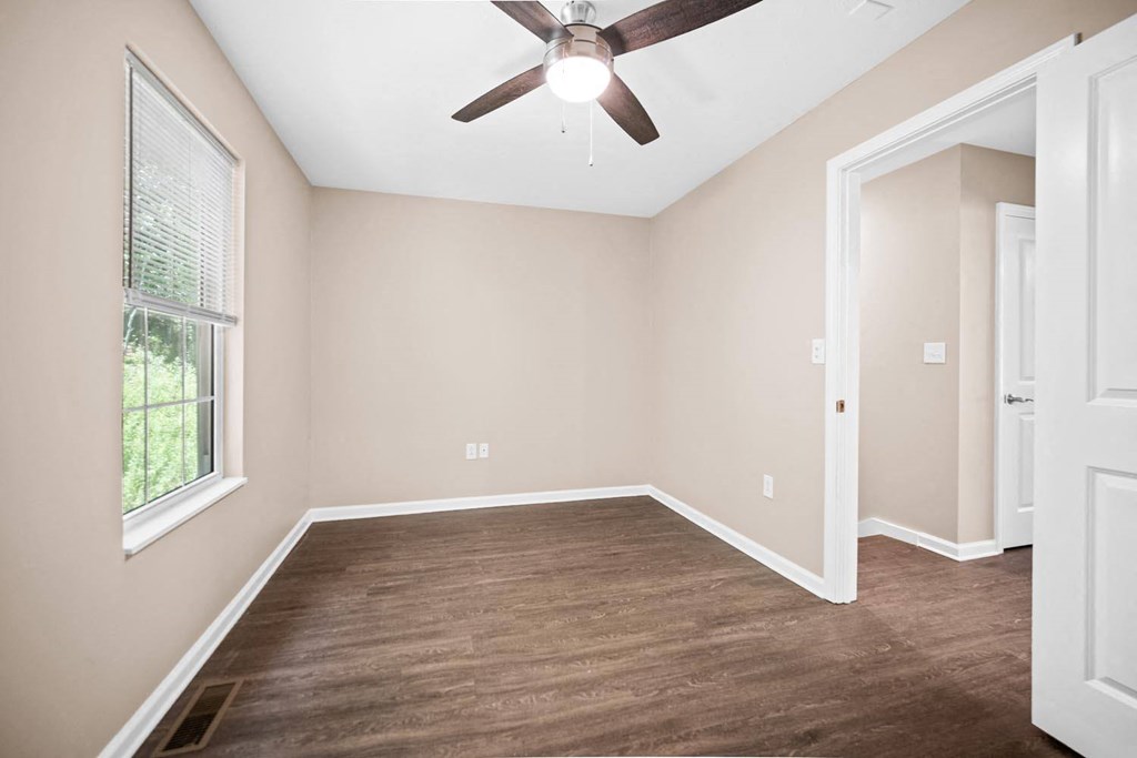 an empty room with a ceiling fan and a window