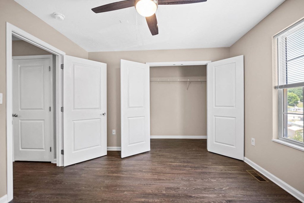 an empty bedroom with a closet and a ceiling fan