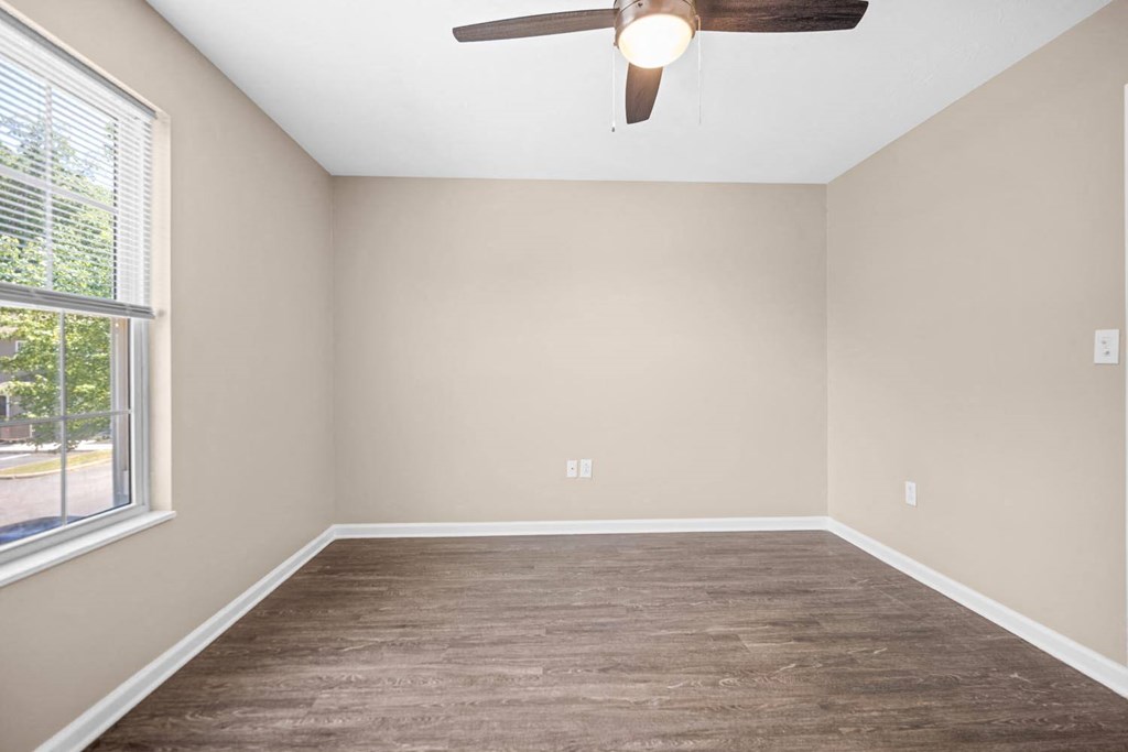 an empty bedroom with a ceiling fan and a window