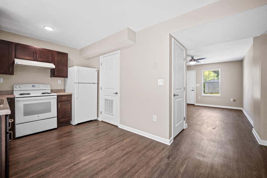 an empty kitchen with white appliances and wood floors