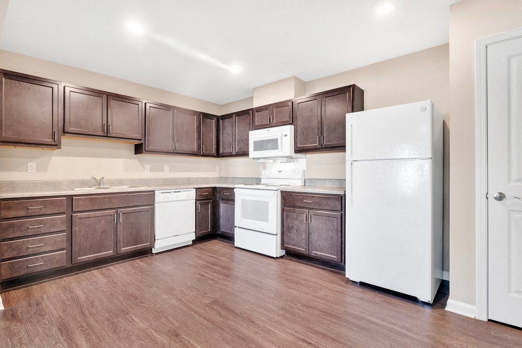 a large kitchen with white appliances and brown cabinets