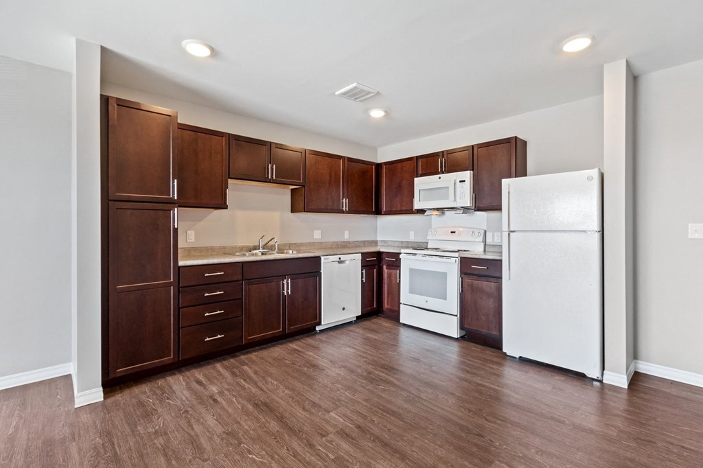 an empty kitchen with white appliances and wooden cabinets