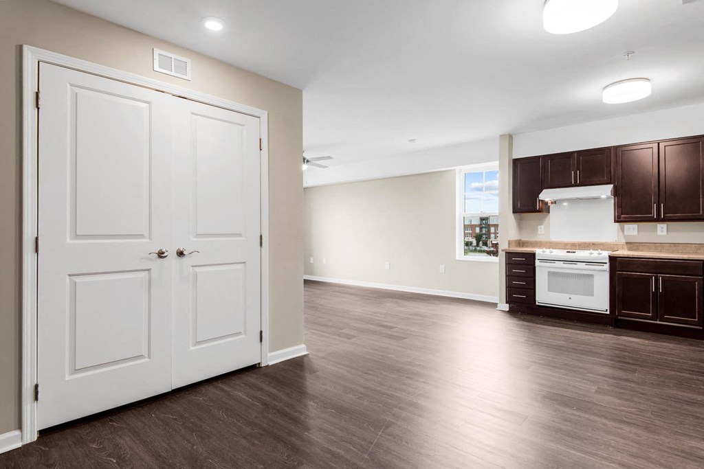 an empty living room with a kitchen in the background