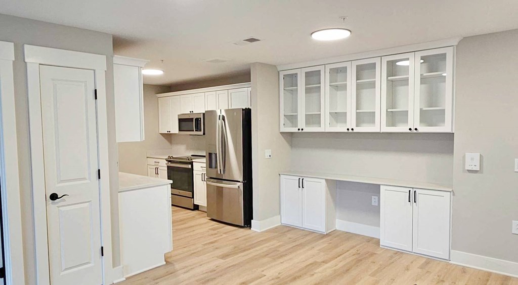 an empty kitchen with white cabinets and a refrigerator