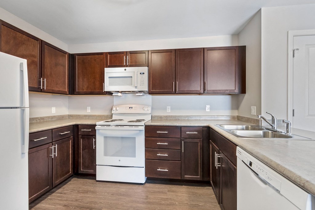 an empty kitchen with white appliances and wooden cabinets