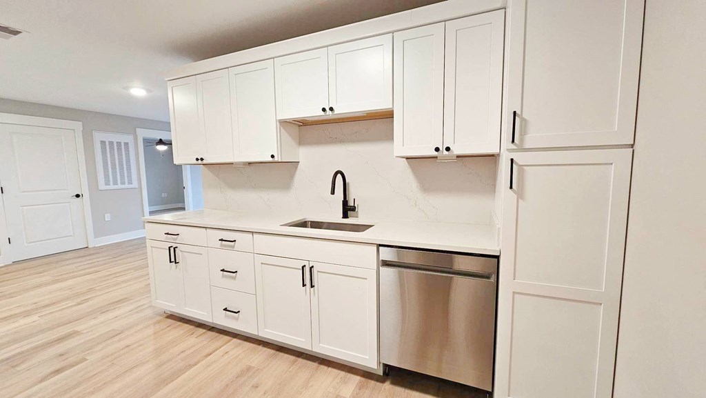 a kitchen with white cabinets and a stainless steel dishwasher