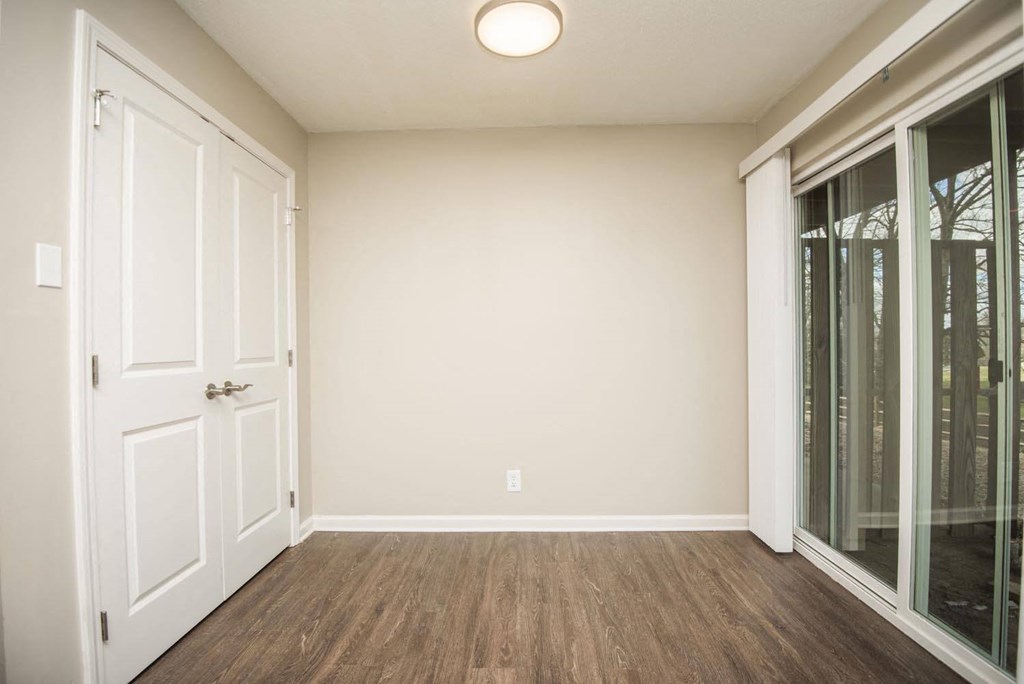 an empty living room with a door to a mirrored closet