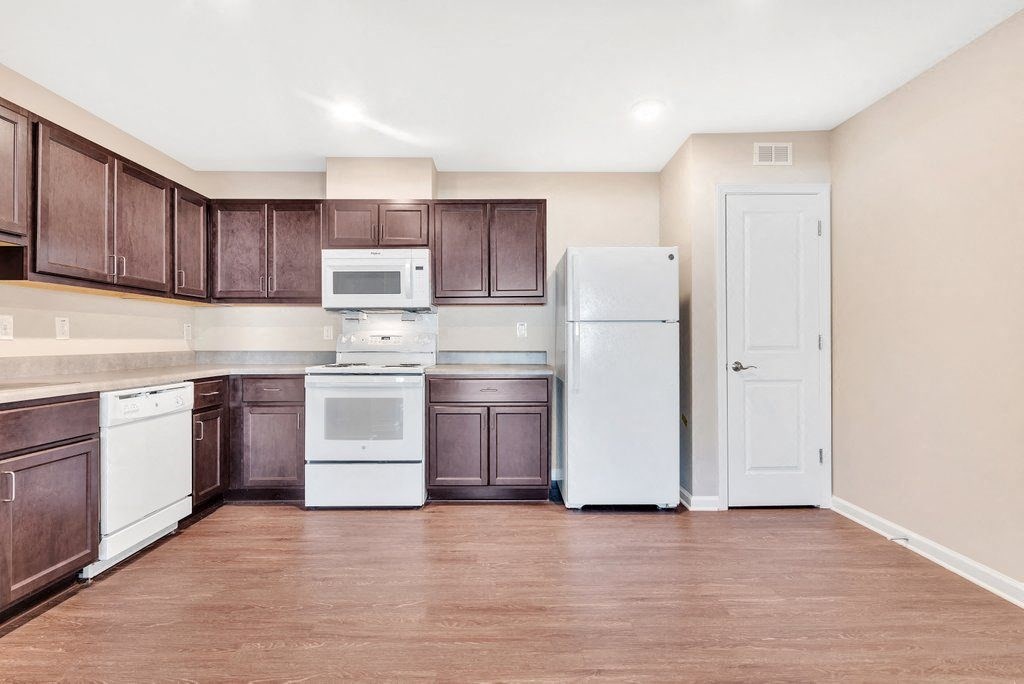 an empty kitchen with white appliances and brown cabinets