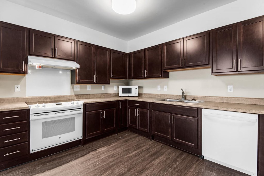 a kitchen with dark wood cabinets and white appliances
