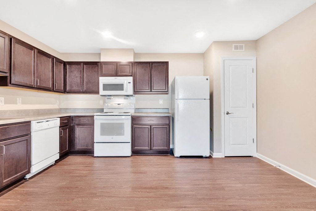 an empty kitchen with white appliances and brown cabinets
