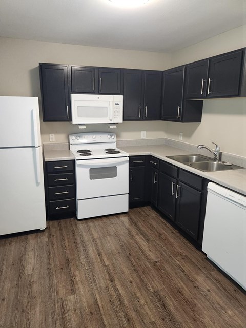 A kitchen with black cabinets and white appliances.