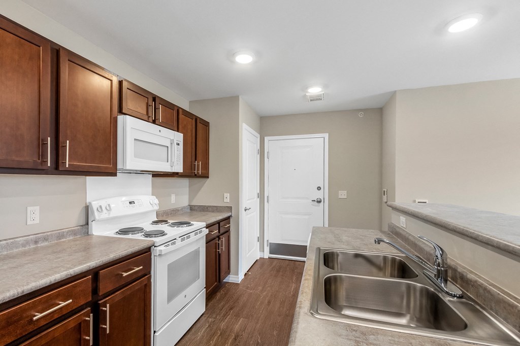an empty kitchen with white appliances and wooden cabinets