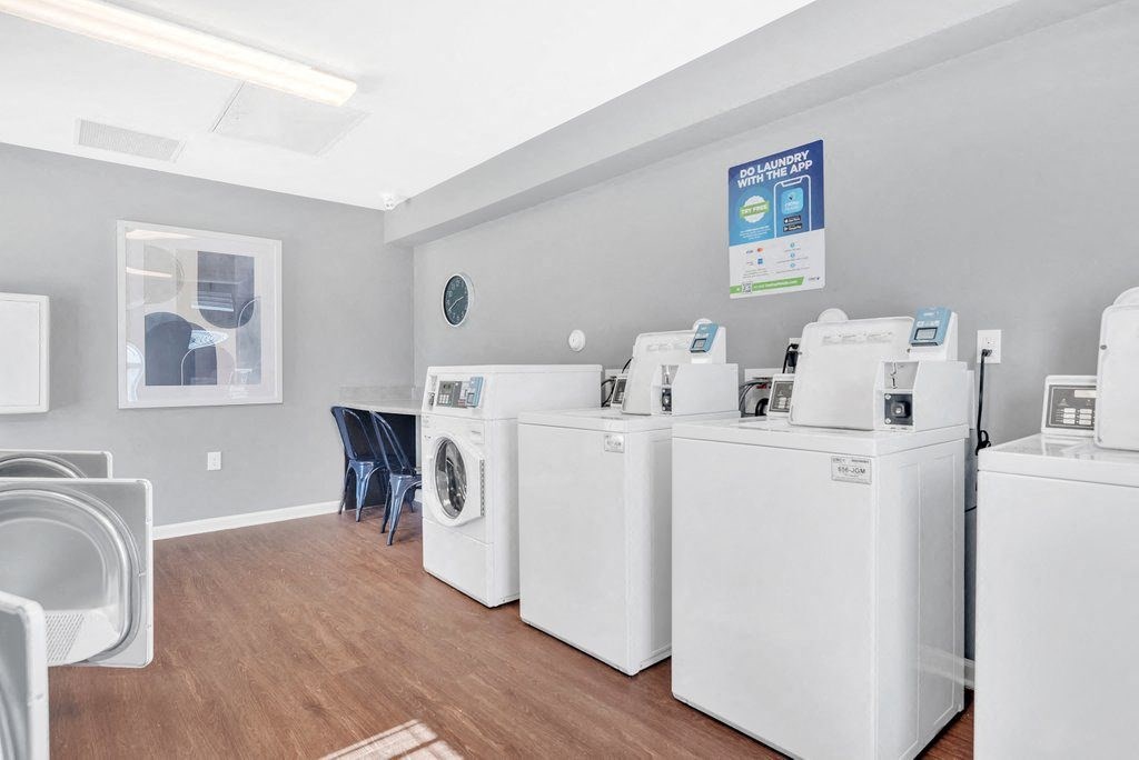 a laundry room with four washes and a table with a chair