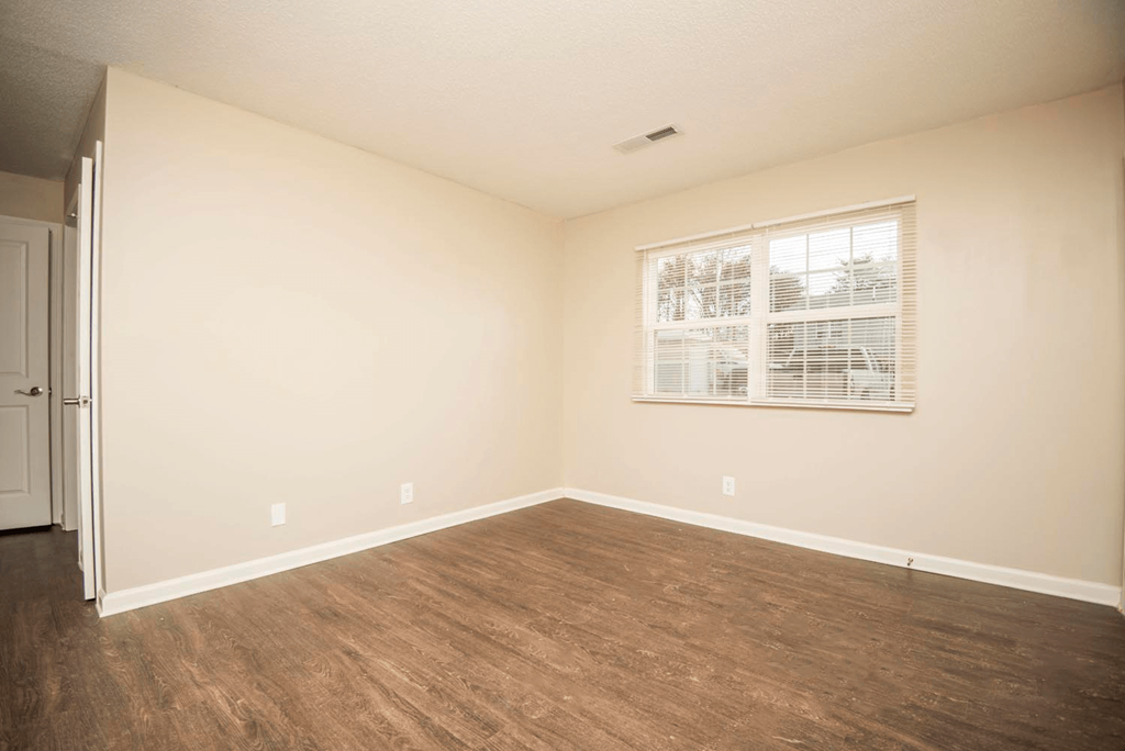 an empty living room with a window and wood flooring