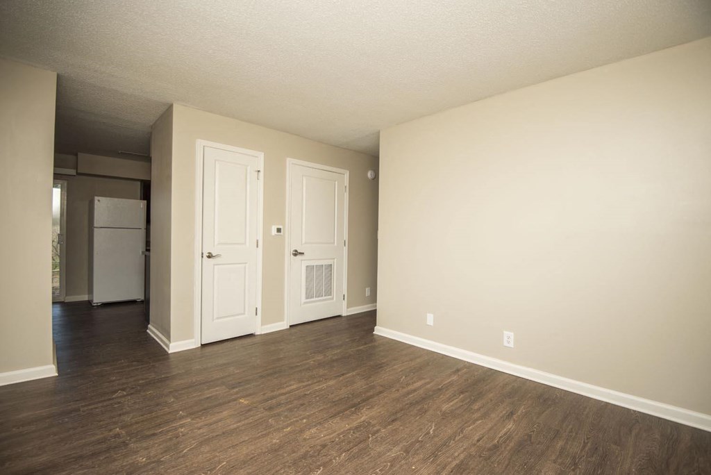 an empty living room with wood floors and a white door