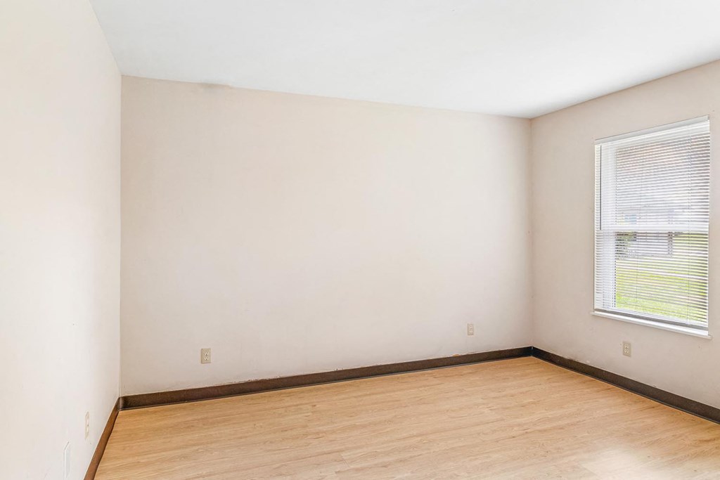 a bedroom with white walls and a window