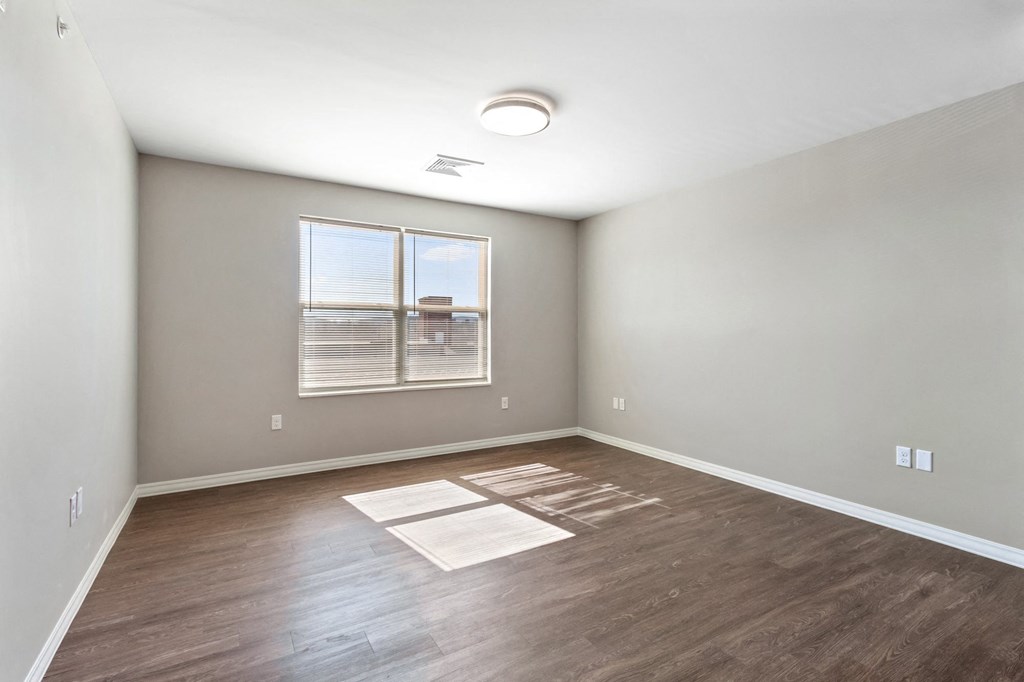 an empty room with wood flooring and a window