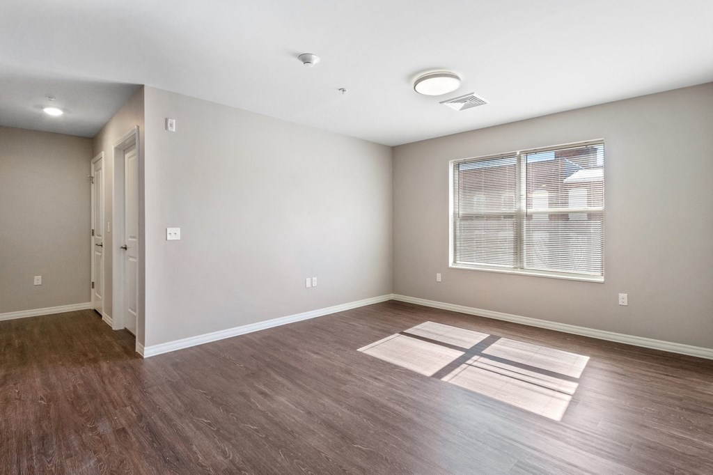 an empty living room with wood flooring and a window