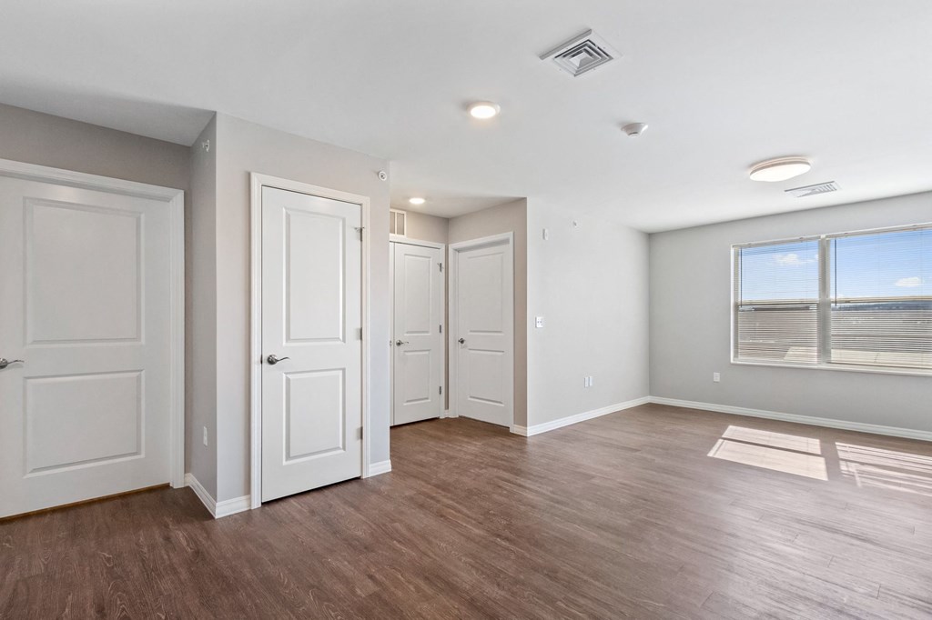 an empty living room with white doors and a window