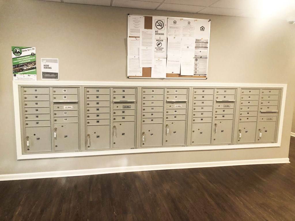 a bunch of mailboxes on a wall with a bulletin board above them