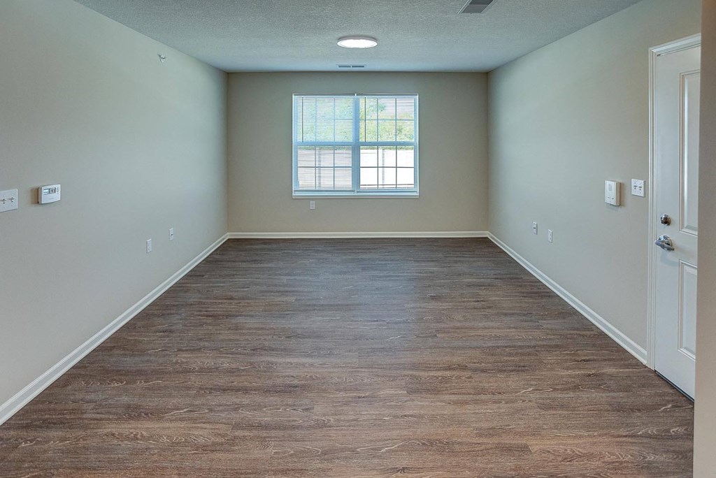 an empty room with wood floors and a window