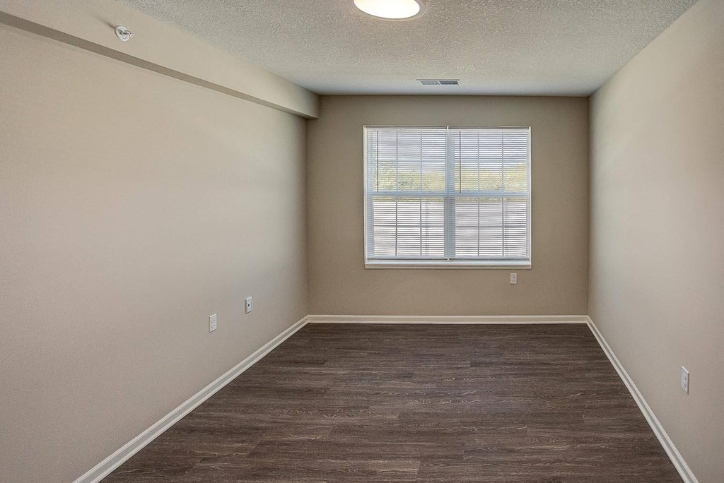 an empty living room with a window and wood floors