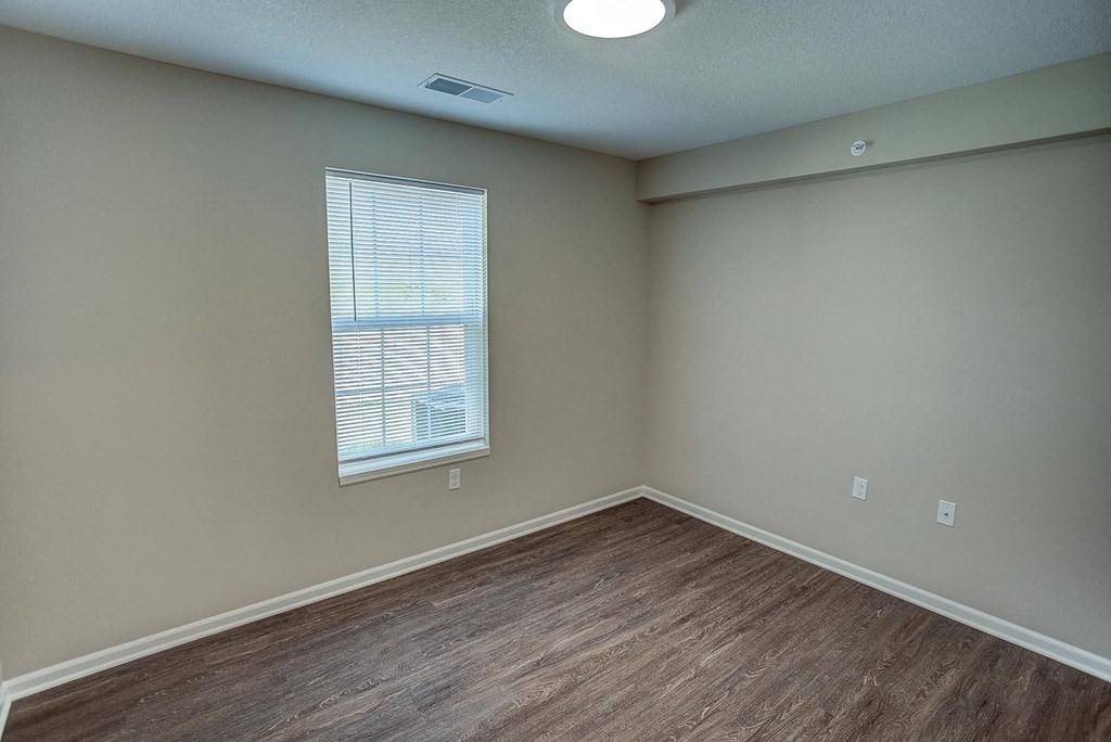 an empty living room with wood floors and a window