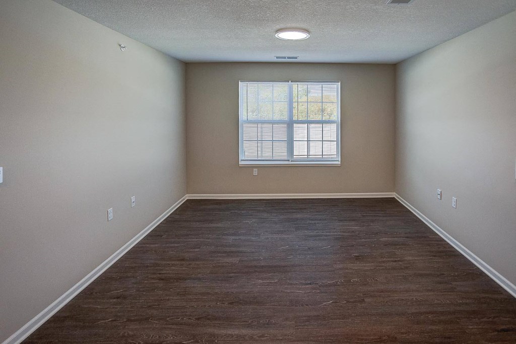 an empty room with wood floors and a window