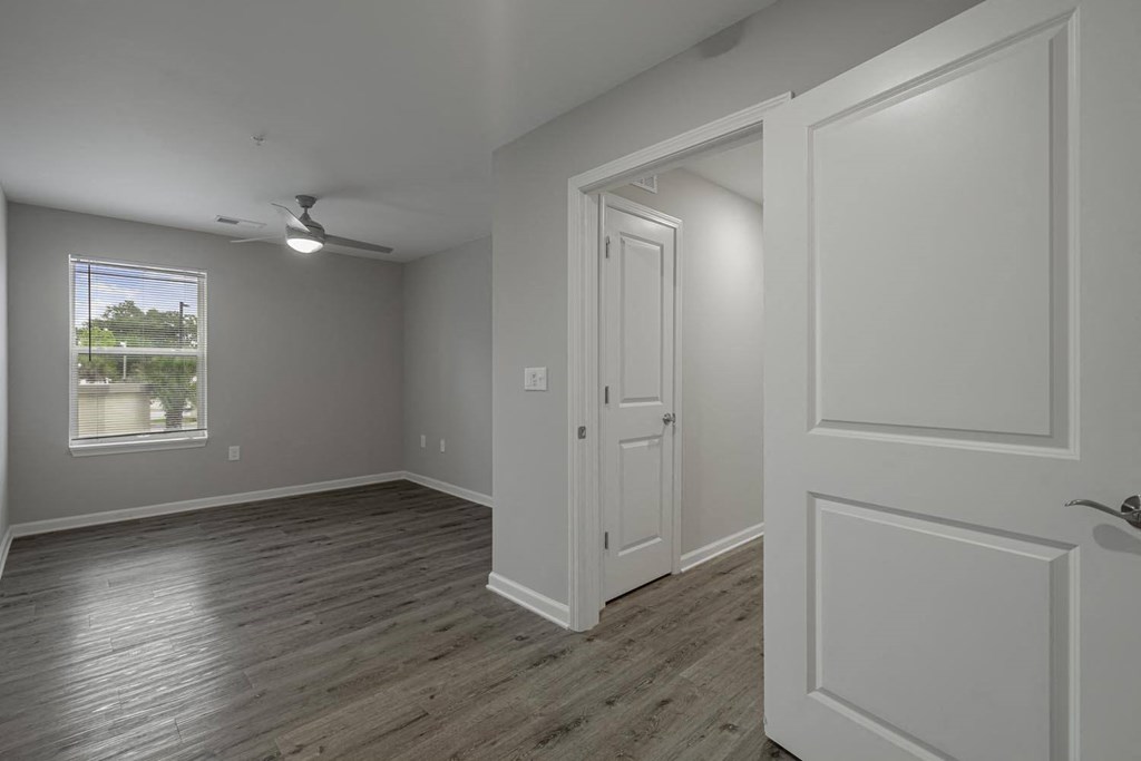 an empty living room with a white door and a window