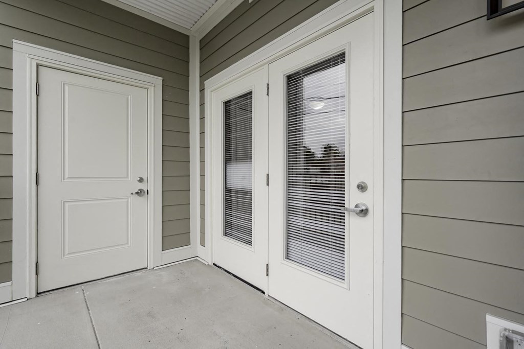 the front door of a home with white doors and a porch