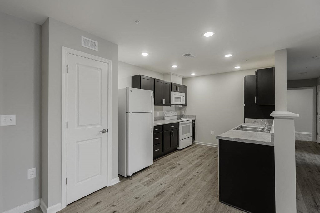 a white kitchen with black cabinets and a white refrigerator