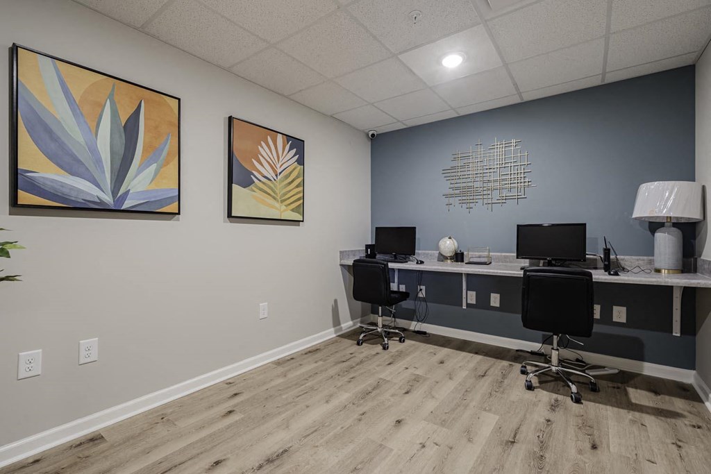an office with two desks and two chairs and two paintings on the wall