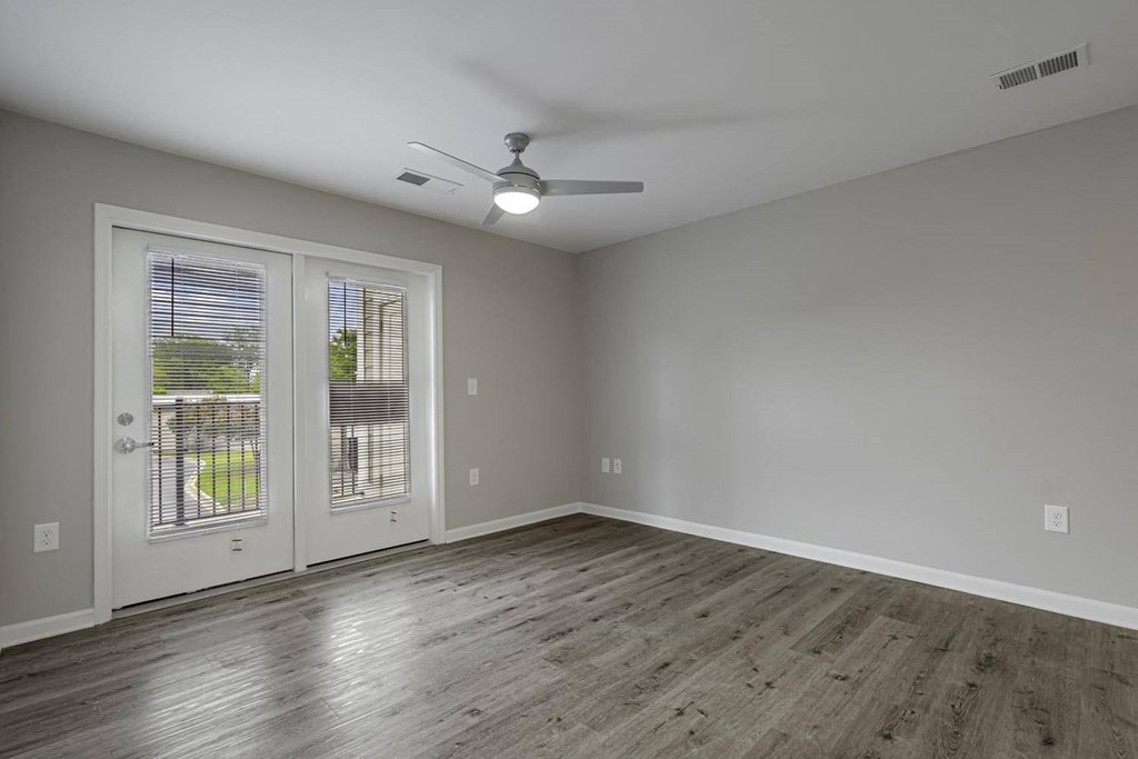 an empty living room with a ceiling fan and a window