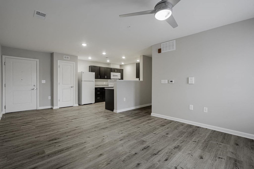 a living room with a kitchen and a ceiling fan