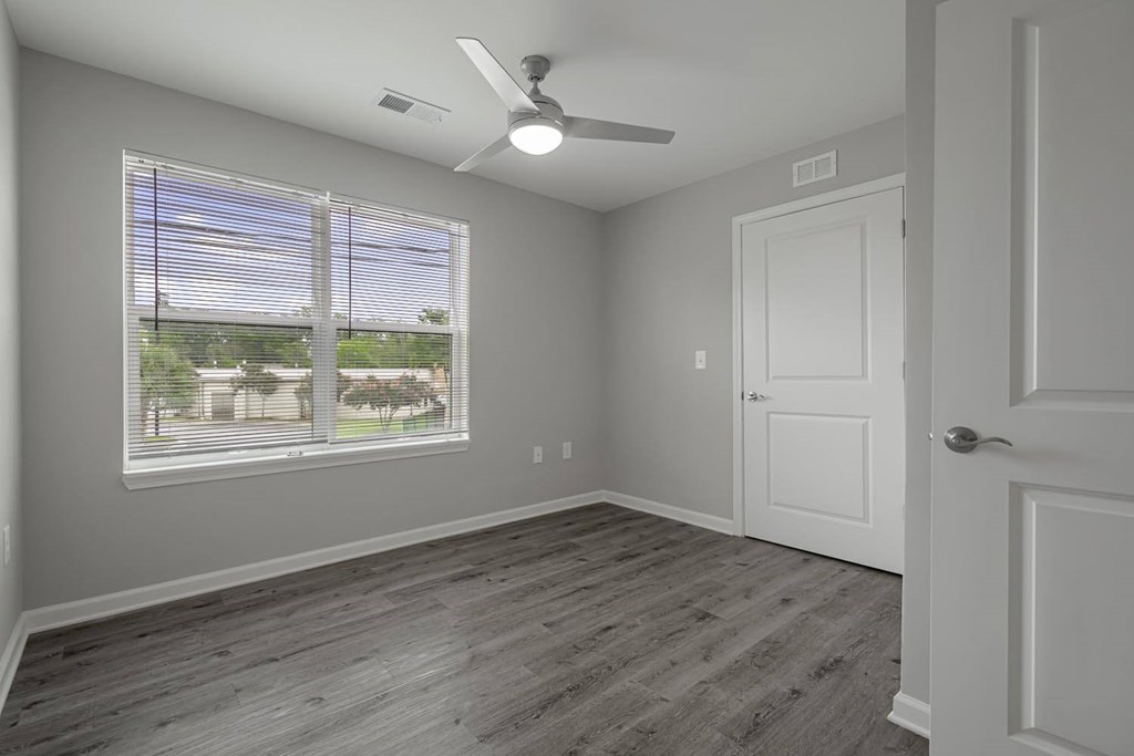 an empty bedroom with a large window and a ceiling fan