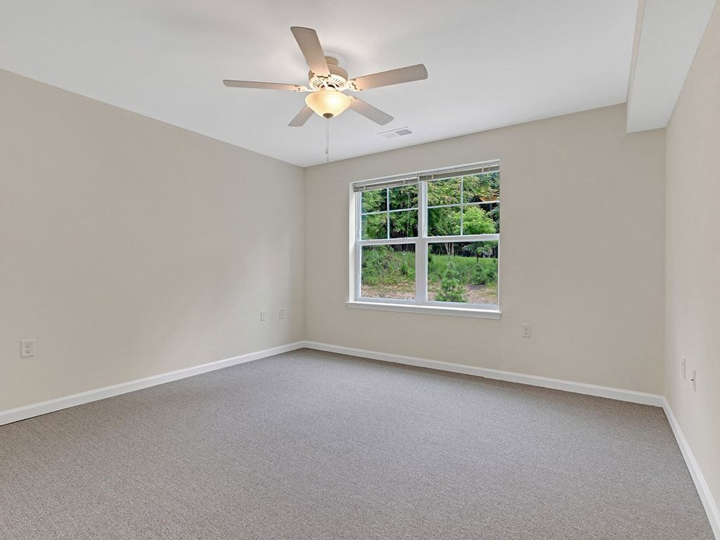 an empty bedroom with a ceiling fan and a window