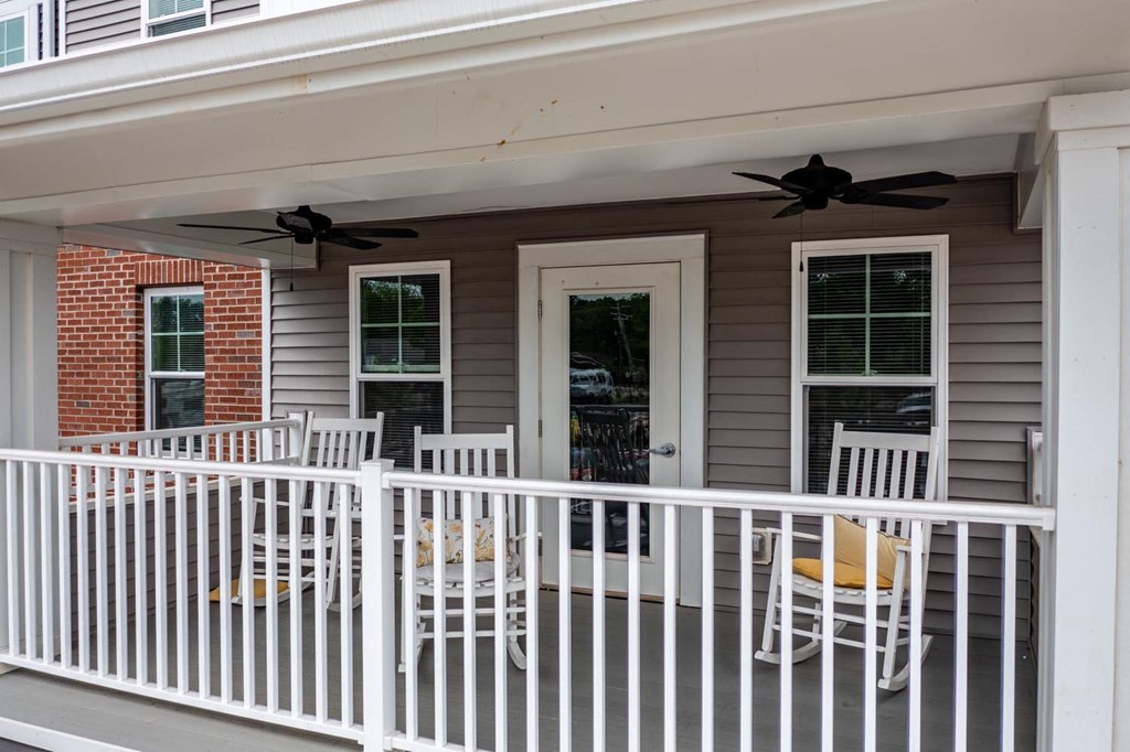 a porch with rocking chairs and two ceiling fans