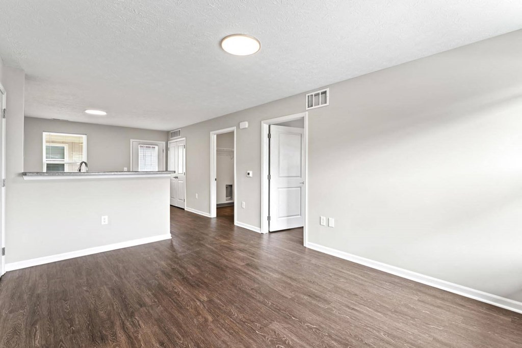 an empty living room and kitchen with a hard wood floor