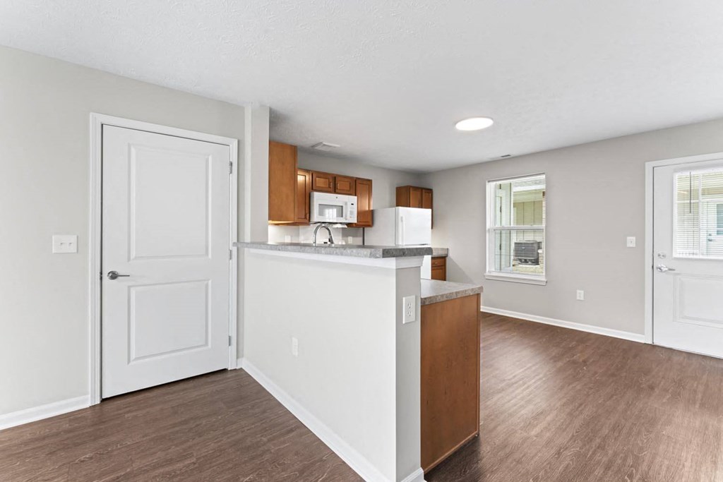 an empty living room and kitchen with a counter top