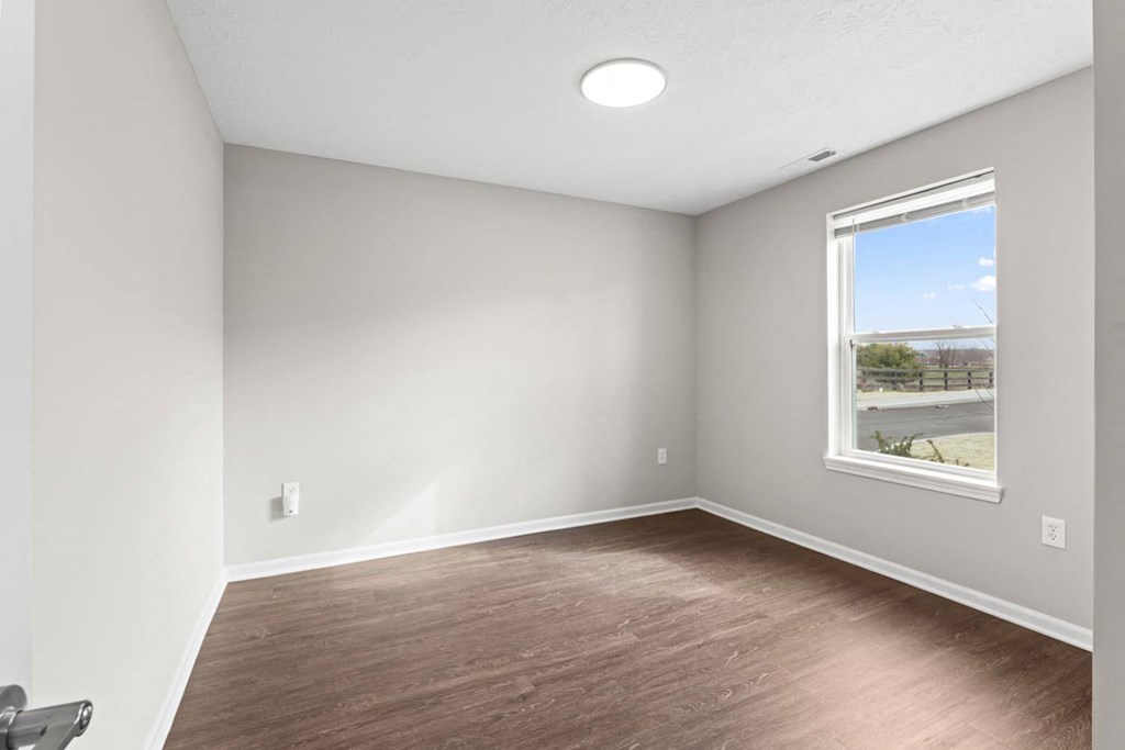 an empty room with wood floors and a window