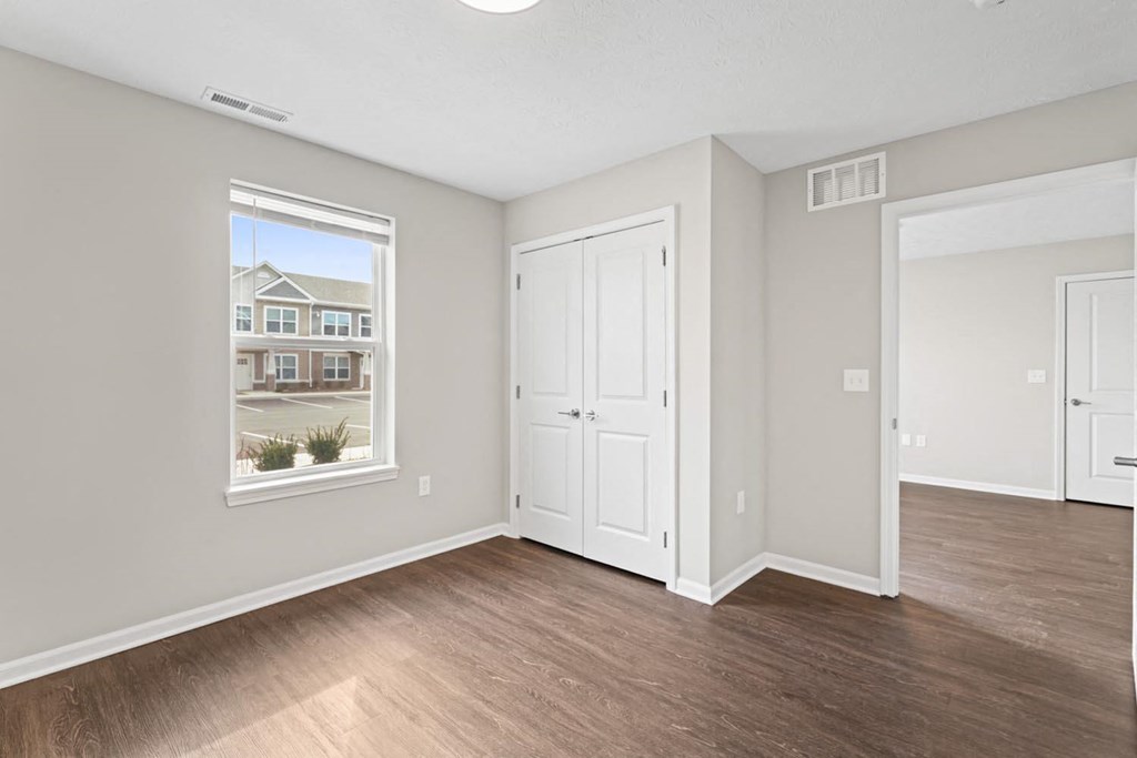 an empty living room with wood floors and a window