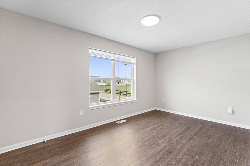 an empty living room with wood floors and a window