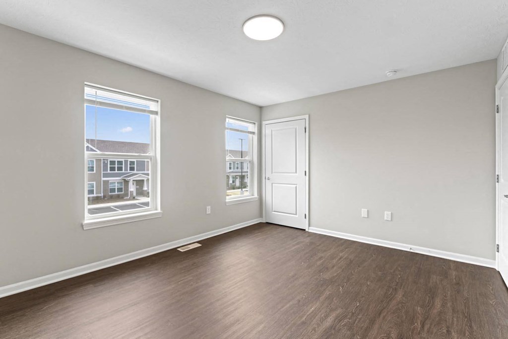 an empty living room with wood flooring and a window