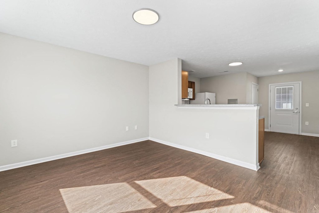 the living room and kitchen of an empty house with wood flooring