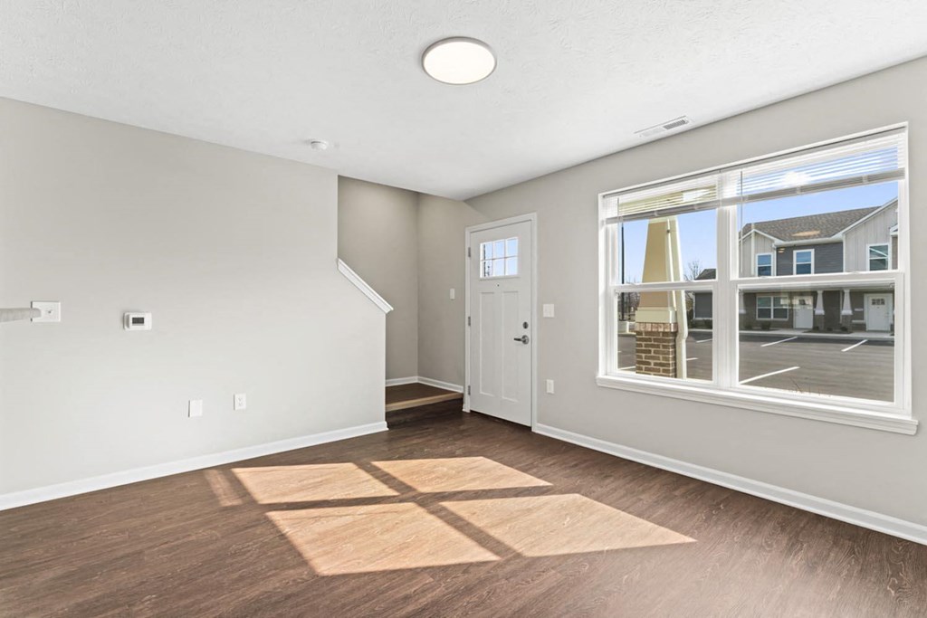 a living room with a large window and hardwood floors