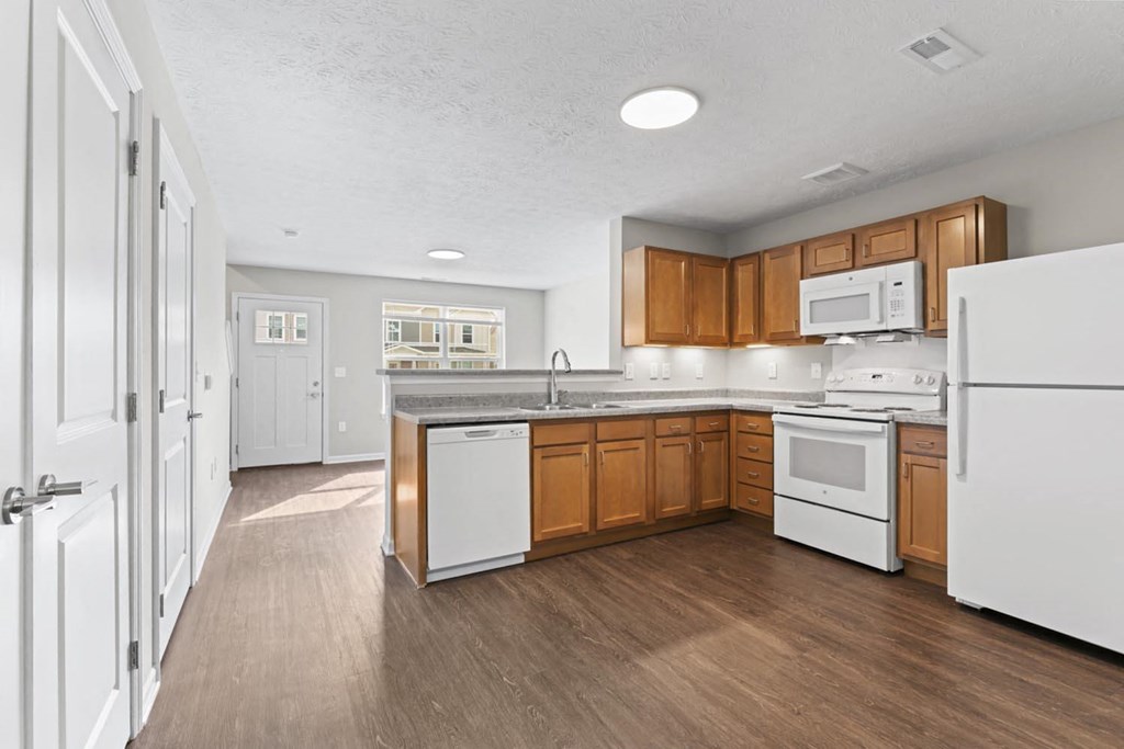 a large kitchen with wooden floors and white appliances